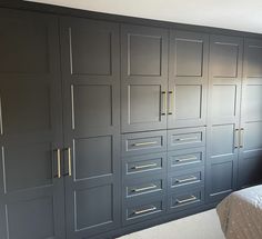 a bed sitting next to a large gray cabinet with drawers on each side and a window above it