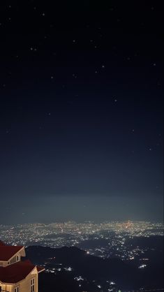 the night sky is lit up with stars and moon over a cityscape in the distance