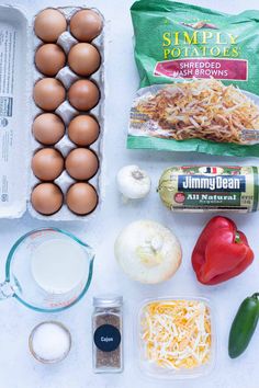 ingredients to make an egg dish laid out on a white counter top, including eggs, cheese, tomatoes, onions, and peppers