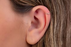 a woman's ear with a single diamond in it