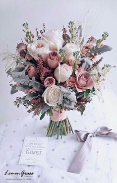 a bouquet of flowers sitting on top of a table next to a card and ribbon