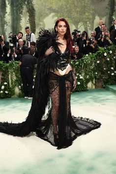 a woman with red hair in a black dress and feathers on her body is posing for the camera