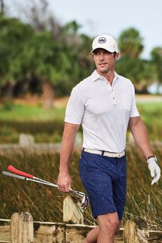 a man in white shirt and blue shorts holding a baseball bat