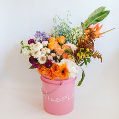 a pink bucket filled with lots of colorful flowers