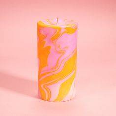 a pink and yellow marbled candle on a pink background