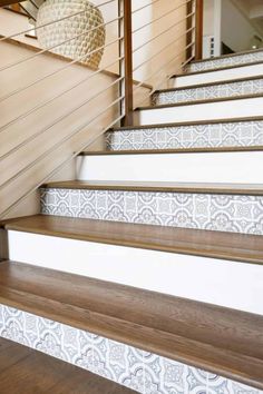 some stairs with white and brown tile on them in front of a wooden handrail