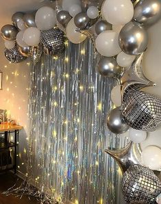 silver and white balloons are hanging from the ceiling