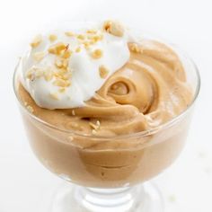 a dessert in a glass bowl topped with whipped cream and nuts