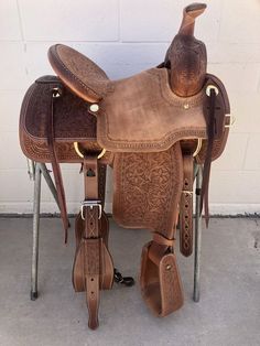 a saddle with two boots on it sitting in front of a wall