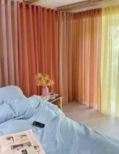 a bed with blue sheets and pillows in front of colorful curtains