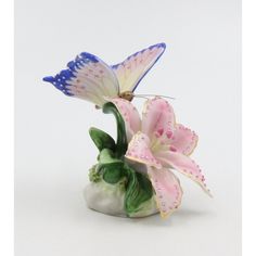 two pink and white flowers in a vase with butterfly wings on the top of it