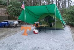 a tent with an american flag on top and picnic table in the back ground next to it