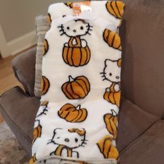 a hello kitty blanket sitting on top of a couch next to a cat and pumpkin