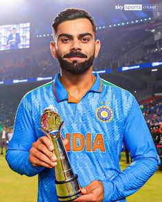 a man with a beard holding a trophy in his right hand and looking at the camera