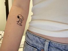 a woman's arm with a small tattoo of a snoopy character on it