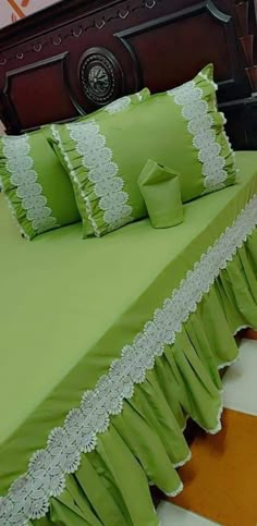 a bed with green sheets and pillows on it