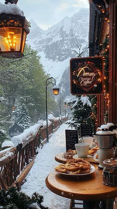 a wooden table topped with plates of food next to a snow covered mountain side restaurant