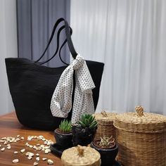 a black purse sitting on top of a wooden table next to potted plants and baskets