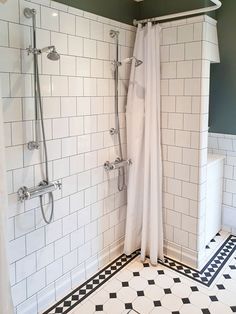 a bathroom with black and white tile flooring, shower head and handrails