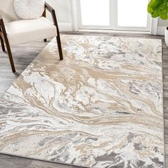 a white and beige area rug with an abstract design on the floor in front of a chair