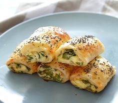 there are four pieces of bread on the plate with spinach and cheese rolls in it