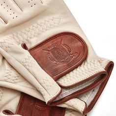 a pair of white leather gloves with brown stitching on the wrist and palm areas