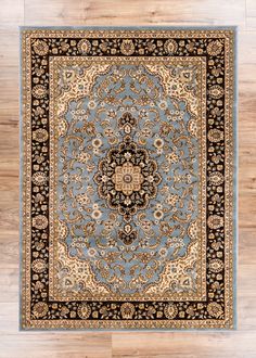 a blue rug with an ornate design on the center and black border, in front of wooden flooring