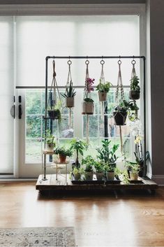 an indoor plant stand with potted plants hanging from it's sides in front of a sliding glass door