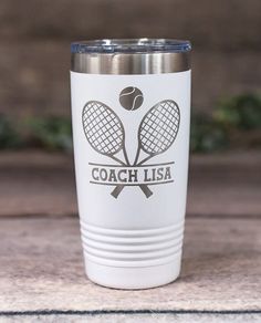 a white tumbler cup with two tennis racquets and the words coach usa on it