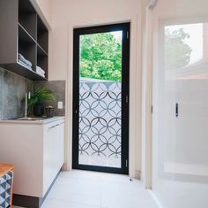 an open door leading to a kitchen with white tile flooring and black glass doors