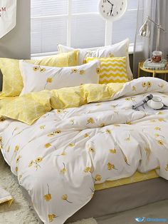 a bed with yellow and white comforters in front of a clock on the wall