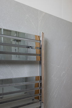 a bathroom with marble walls and flooring next to a metal rack on the wall