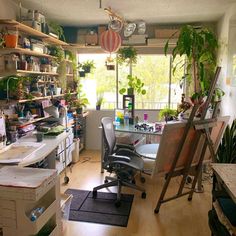 a room filled with lots of plants and desks next to shelves full of books