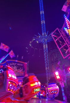 an amusement park ride at night with lights on the rides and people riding in it