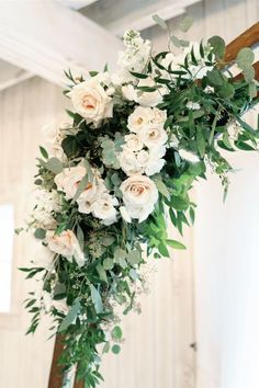 white flowers and greenery are hanging from the ceiling