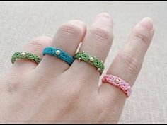 a woman's hand with three crocheted rings on it, one in pink and the other in green