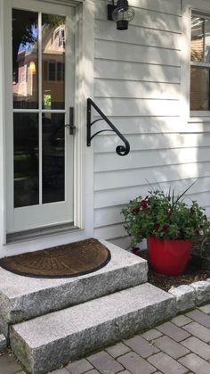 the front door of a house with potted plants on the steps and an entry mat