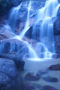 there is a waterfall in the middle of some rocks with water running down it's sides