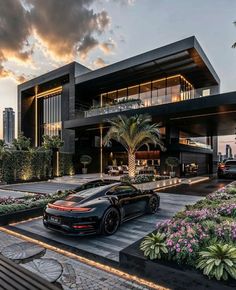 a black sports car is parked in front of a building with flowers and palm trees