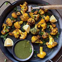 roasted cauliflower with pesto sauce and lemon wedges