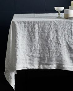 two white candles are sitting on top of a linen tablecloth that has been folded over