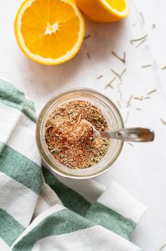 an orange and spices in a jar next to some sliced oranges on a towel