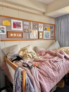 an unmade bed in a bedroom with pictures on the wall