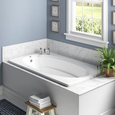 a white bath tub sitting next to a window in a blue bathroom with pictures on the wall