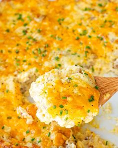 a wooden spoon scooping out some food from a casserole dish with cheese