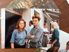 two people standing next to each other in front of a table with pictures on it