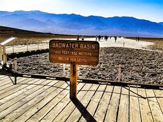 there is a sign that says badwater basin on the side of a wooden boardwalk