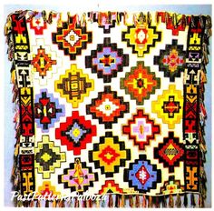 a multicolored rug with fringes and designs on the front, hanging from a wall