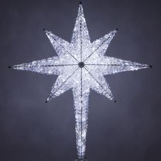 a lighted snowflake star ornament on a black background