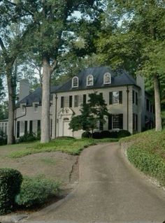 a large white house sitting on the side of a lush green hillside next to trees